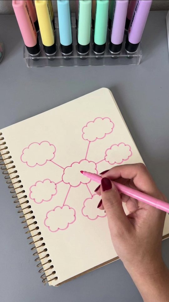 A hand draws a mind map in pink marker, stops, tears the page out.
