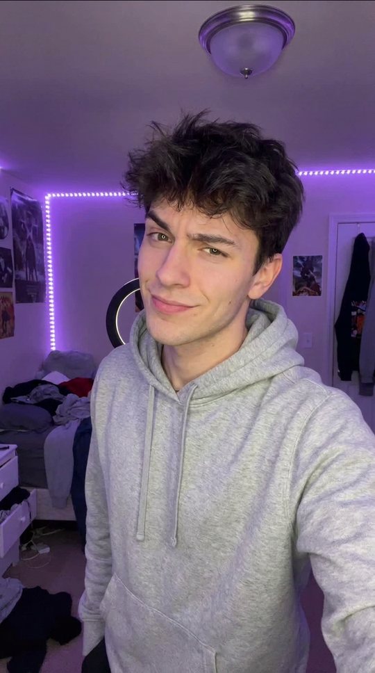 He faces the camera in a plain hoodie, eyebrow up.