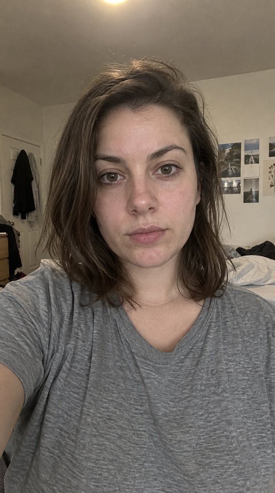 A flat, unflattering selfie in a messy room.